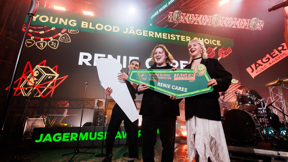 Three people on a concert stage holding award plaques, with large Jäger Music branding and stage lights in the background.
