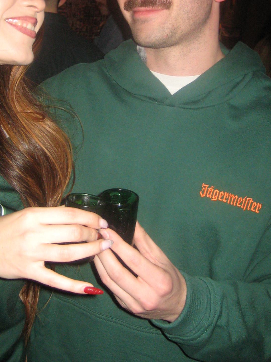 Person wearing a green Jägermeister hoodie with the orange Jägermeister wordmark on the chest.