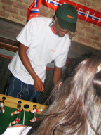 Person playing table football with a brick wall and red and white banner in the background.