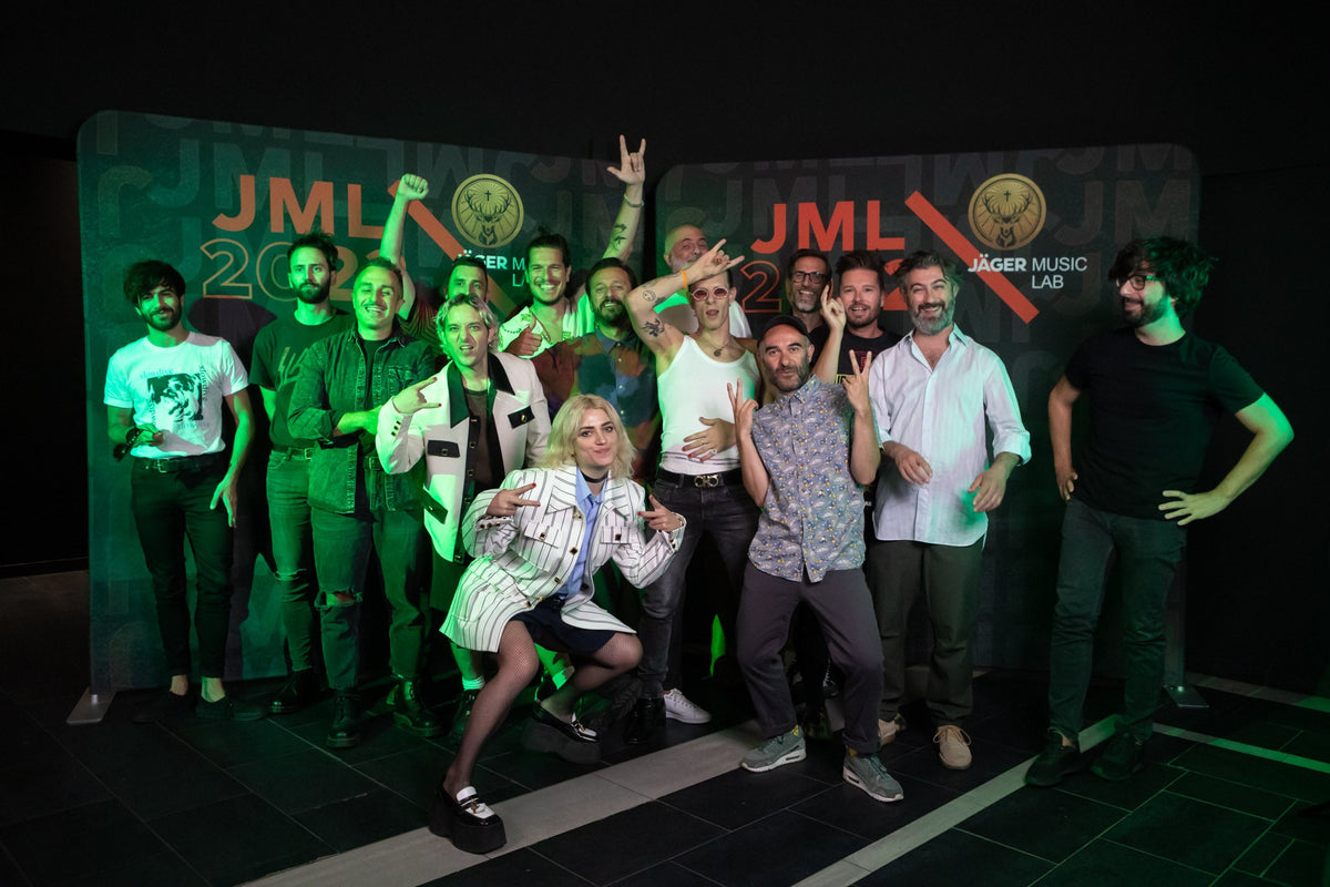 Group photo of participants posing in front of a Jäger Music Lab (JML) event backdrop, with green stage lighting and JML 2024 branding visible in the background.