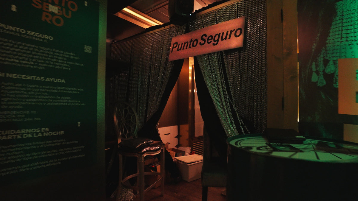 A dimly lit interior scene with a hanging sign reading 'Punto Seguro' above dark curtains, with furniture and a table visible in a moody room. Spanish text appears on a green panel to the left.