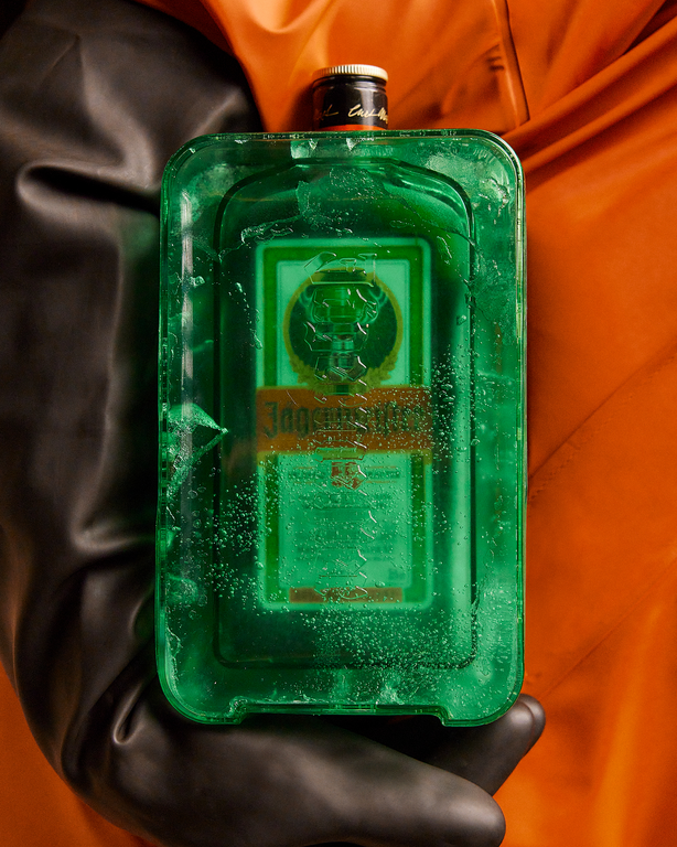 Green frozen bottle of Jägermeister wrapped in Coldblock held by a gloved hand a