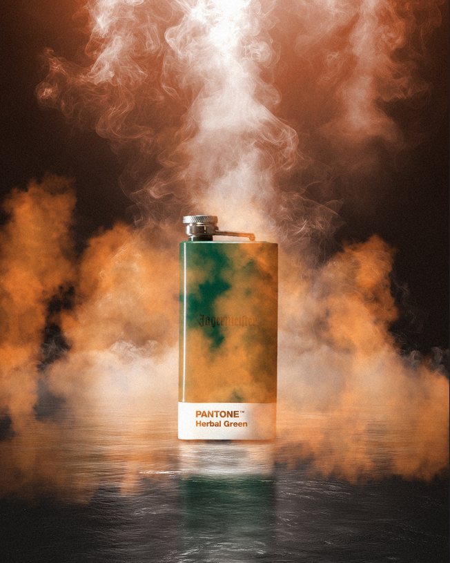 Pantone-flacon met groene kleurstaal, omringd door kleurrijke rook op een donkere achtergrond