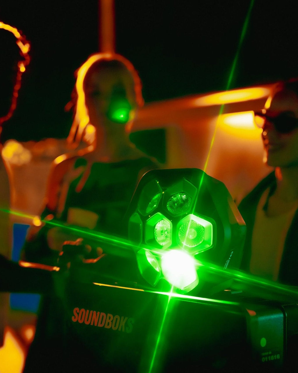 Green shining LIghtboks with placed on a Soundboks surrouended by people partying 