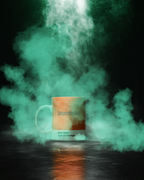 Cană cu textul „Jagermeister” și „Pantone Culture Orange”, înconjurată de fum colorat pe fundal întunecat