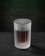 White Jägermeister shot glas with embossed Jägermeister wordmark
and liquid in it